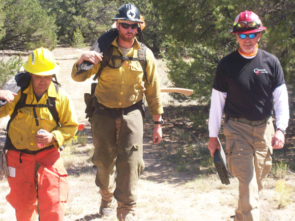 Mark Thomas (right) walks with S-212 chainsaws students for field evaluation.